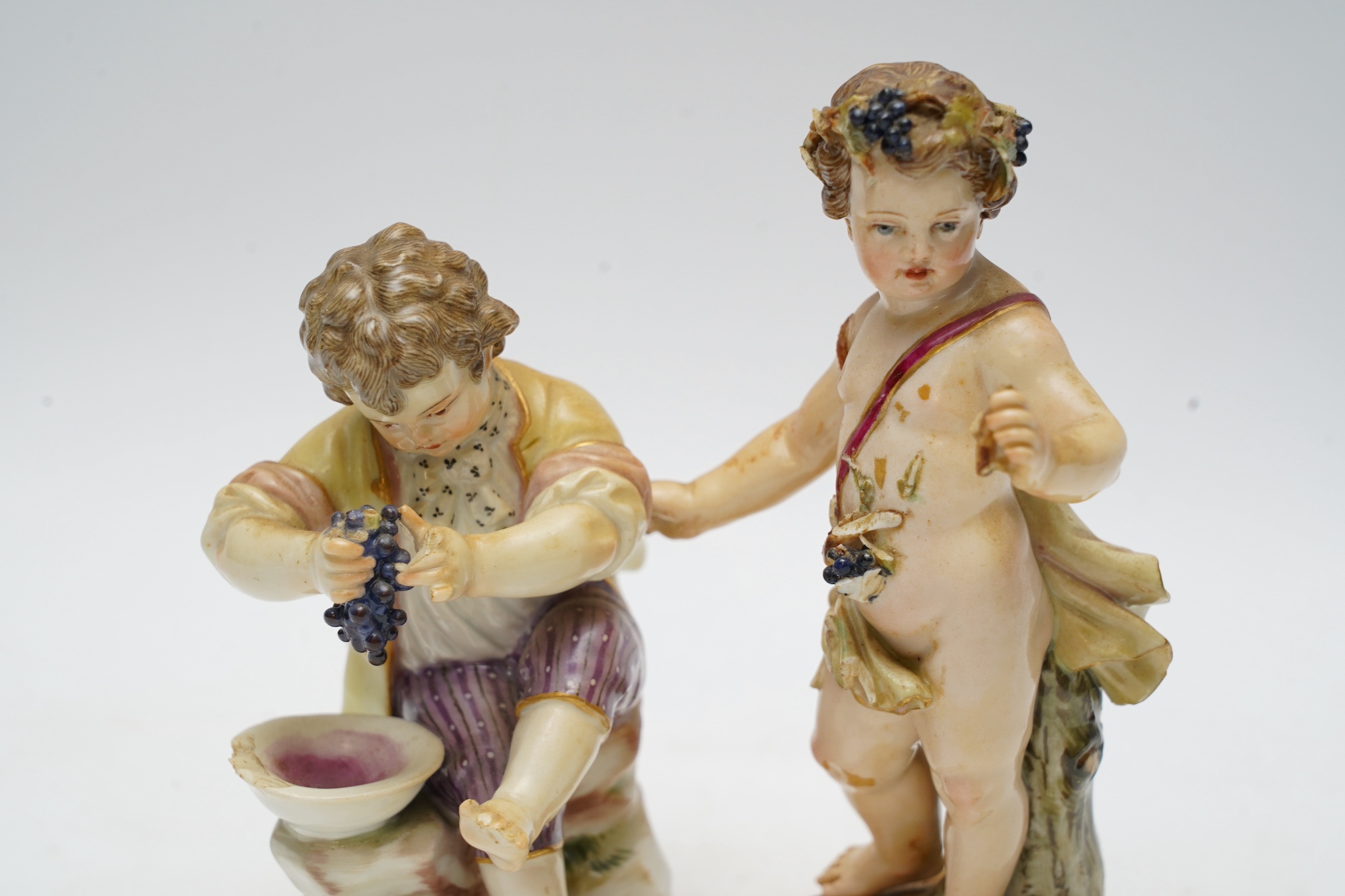 Two Meissen porcelain figures, boys with grapes, largest 13cm high. Condition - poor